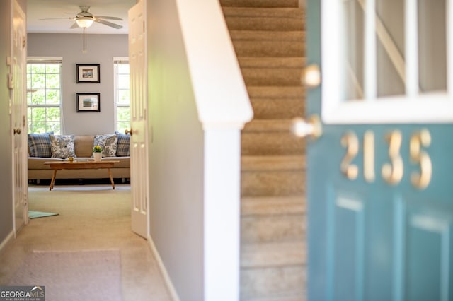 corridor featuring baseboards, carpet, and stairs