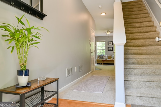 stairs with ceiling fan, baseboards, and visible vents