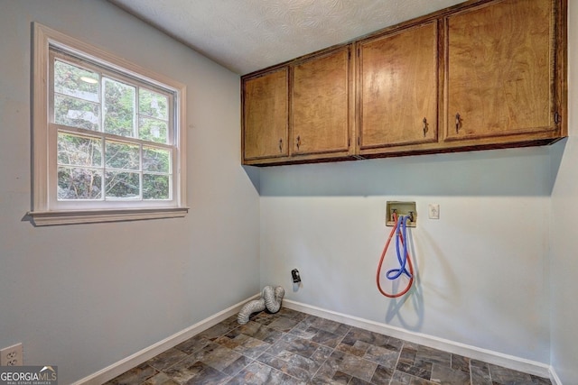 5621 Wildwood Trl, Lithonia, GA 30038 - clothes washing area with stone finish floor, hookup for a washing machine, baseboards, cabinet space, and a textured ceiling