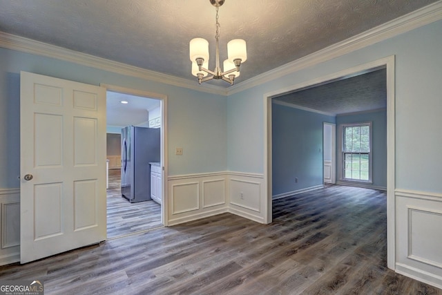 5621 Wildwood Trl, Lithonia, GA 30038 - unfurnished dining area featuring crown molding, a textured ceiling, a wainscoted wall, a notable chandelier, and dark wood-type flooring