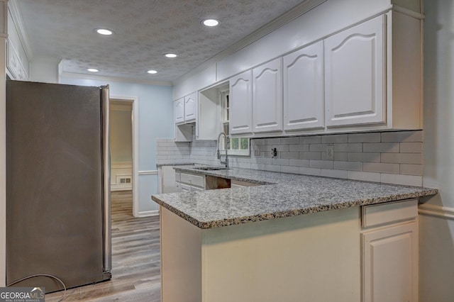 5621 Wildwood Trl, Lithonia, GA 30038 - kitchen featuring light wood finished floors, a peninsula, a sink, freestanding refrigerator, and light stone countertops
