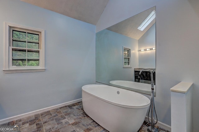 5621 Wildwood Trl, Lithonia, GA 30038 - full bathroom featuring baseboards, vaulted ceiling with skylight, and a freestanding tub