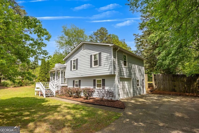 exterior space with concrete driveway, an attached garage, fence, a yard, and stairs