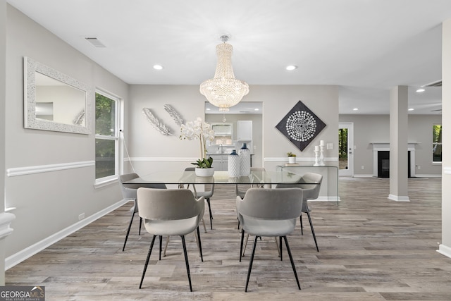 dining space with an inviting chandelier, a wealth of natural light, and wood finished floors