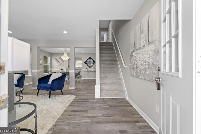 foyer featuring wood finished floors, baseboards, recessed lighting, and stairs