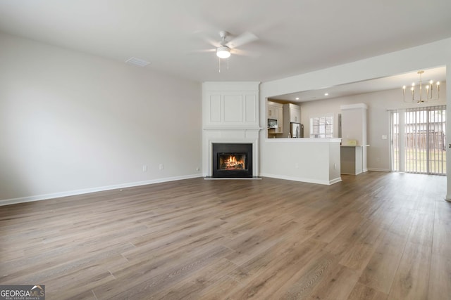 13300 Morris Rd Unit 76, Milton, GA 30004 - unfurnished living room featuring wood finished floors, a chandelier, ceiling fan, a large fireplace, and baseboards