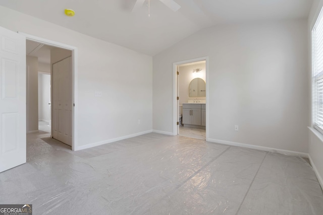 unfurnished bedroom featuring vaulted ceiling, ensuite bath, baseboards, and a ceiling fan