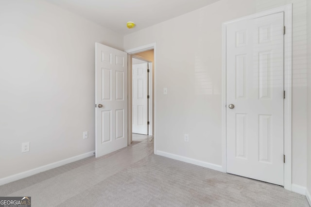 unfurnished bedroom featuring light colored carpet and baseboards