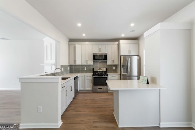 kitchen with a peninsula, light countertops, stainless steel appliances, and backsplash