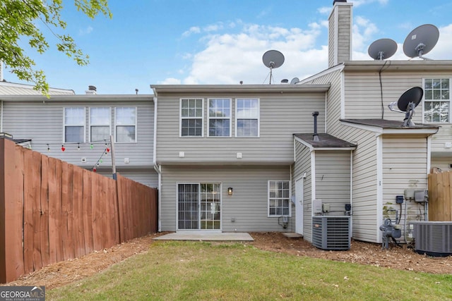 back of property with a lawn, central air condition unit, a patio area, and fence