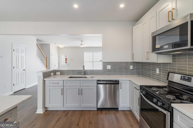 kitchen with ceiling fan, a sink, a peninsula, light countertops, and appliances with stainless steel finishes