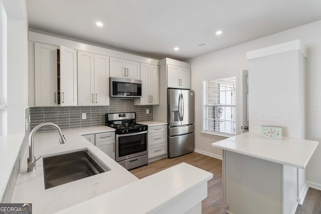 13300 Morris Rd Unit 76, Milton, GA 30004 - kitchen with appliances with stainless steel finishes, light wood-type flooring, a sink, backsplash, and recessed lighting