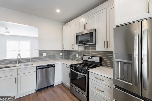 kitchen featuring a sink, tasteful backsplash, ceiling fan, white cabinetry, and appliances with stainless steel finishes