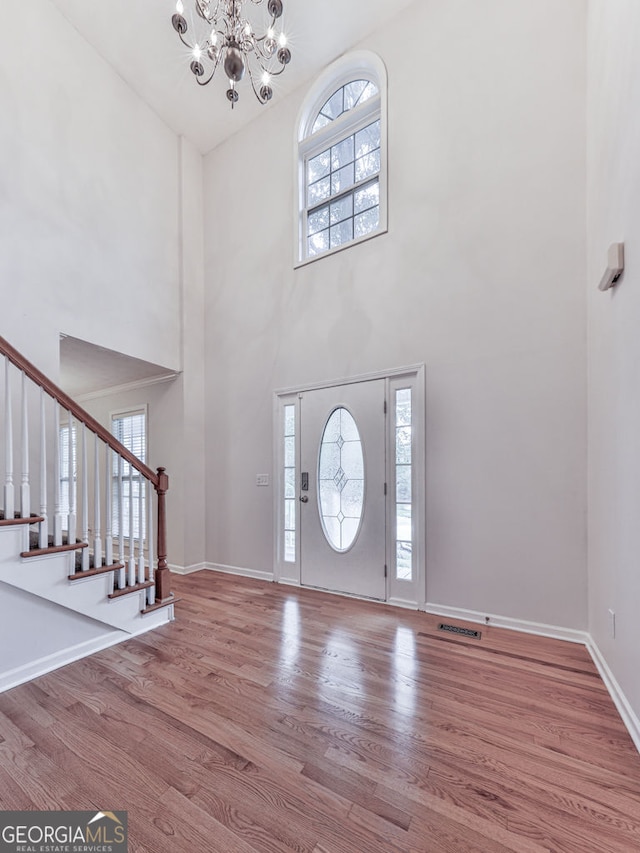 entryway featuring a wealth of natural light, a towering ceiling, and a notable chandelier