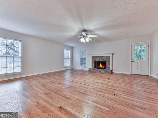 unfurnished living room with a textured ceiling, ceiling fan, and light wood-style floors
