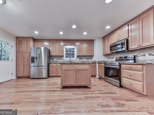 kitchen with light wood finished floors, appliances with stainless steel finishes, and decorative backsplash
