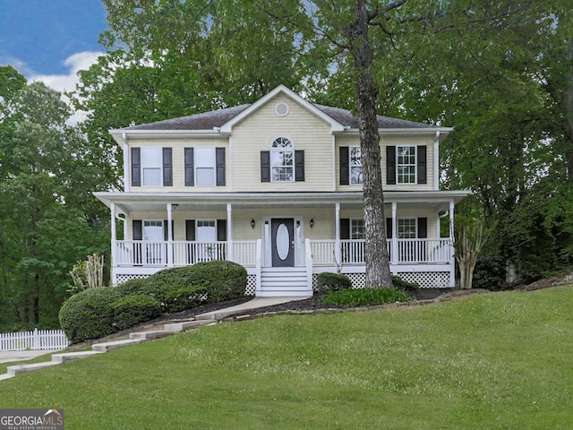colonial inspired home with a porch, a front yard, and fence