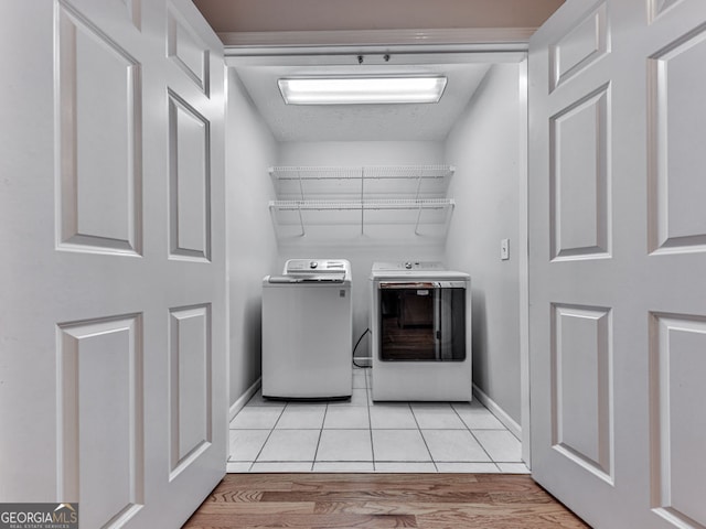laundry area with light wood-type flooring, baseboards, and washing machine and dryer