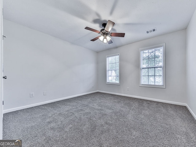 carpeted spare room featuring baseboards, visible vents, and a ceiling fan