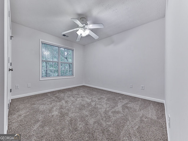 carpeted spare room featuring visible vents, a ceiling fan, and baseboards