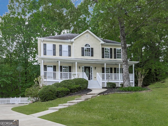 colonial home with a porch, a front lawn, and fence