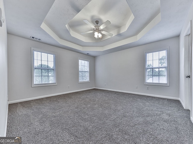 unfurnished room with baseboards, a raised ceiling, and a wealth of natural light