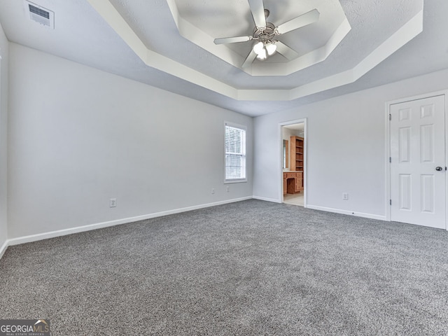interior space featuring a raised ceiling, a ceiling fan, visible vents, and baseboards