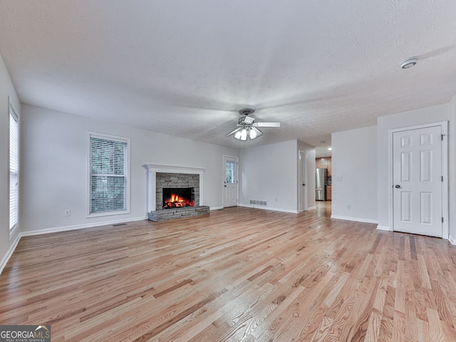 unfurnished living room featuring visible vents, a healthy amount of sunlight, a ceiling fan, and light wood-style floors