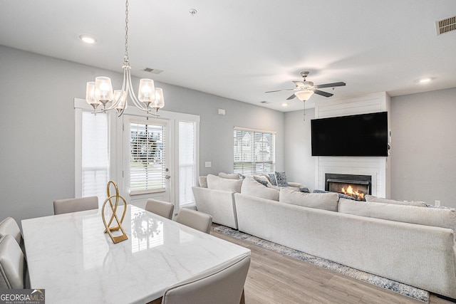 1702 Prospect Way, Conyers, GA 30094 - dining space with wood finished floors, ceiling fan with notable chandelier, a lit fireplace, visible vents, and recessed lighting