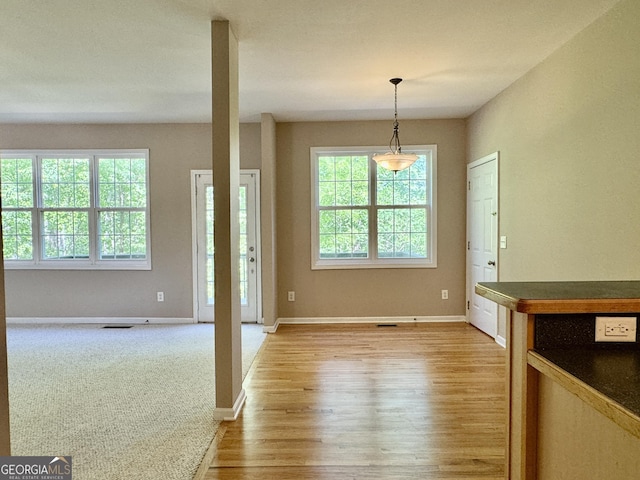 unfurnished dining area with baseboards, light wood-style floors, visible vents, and plenty of natural light