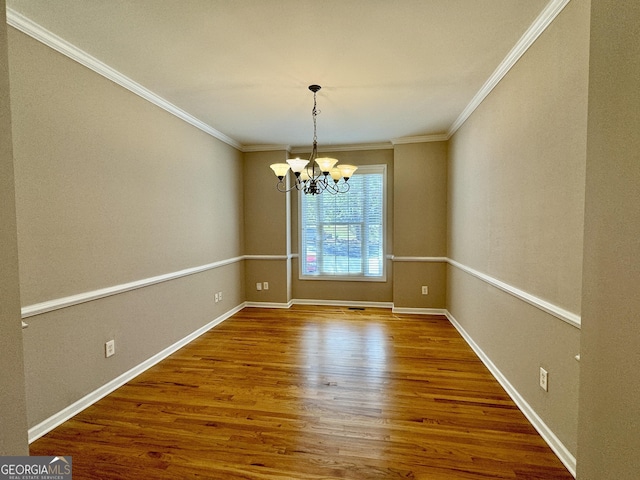 unfurnished dining area featuring baseboards, wood finished floors, an inviting chandelier, and crown molding