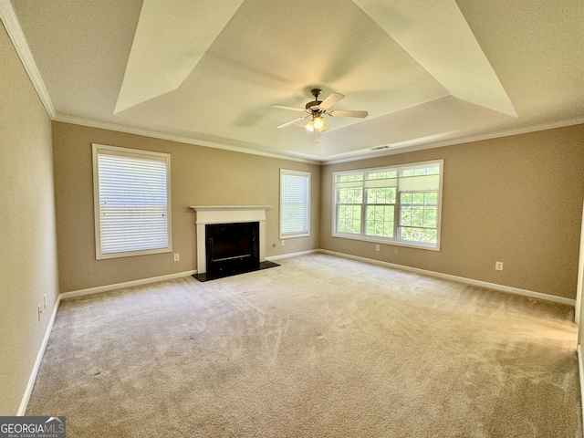 unfurnished living room featuring a raised ceiling, baseboards, carpet, a ceiling fan, and ornamental molding