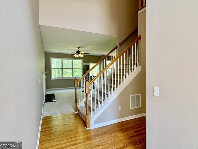 stairway featuring ceiling fan, baseboards, wood finished floors, and visible vents