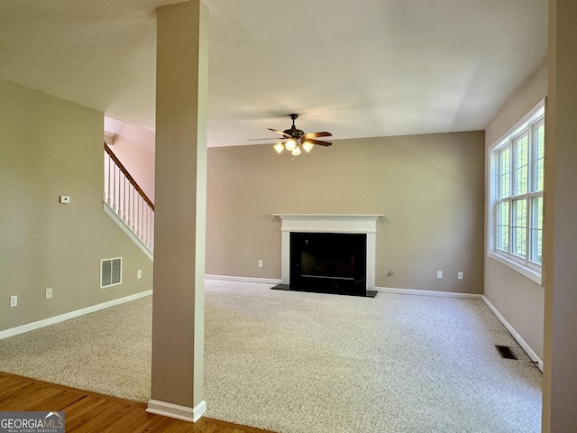 unfurnished living room with baseboards, a ceiling fan, visible vents, and a fireplace