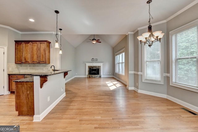 kitchen featuring a breakfast bar area, light wood-type flooring, brown cabinets, ceiling fan with notable chandelier, and open floor plan