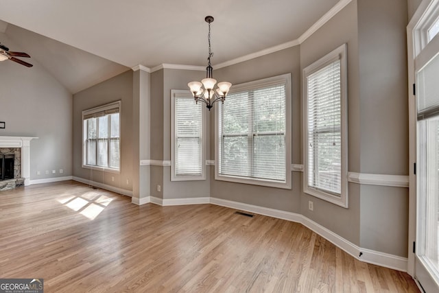 unfurnished dining area featuring visible vents, a fireplace, baseboards, ceiling fan with notable chandelier, and light wood finished floors