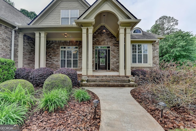 entrance to property featuring a porch and brick siding