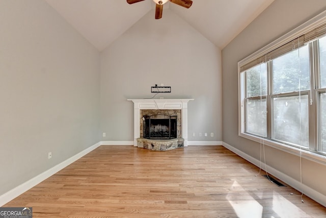 unfurnished living room with light wood-style floors, a fireplace, high vaulted ceiling, a ceiling fan, and baseboards