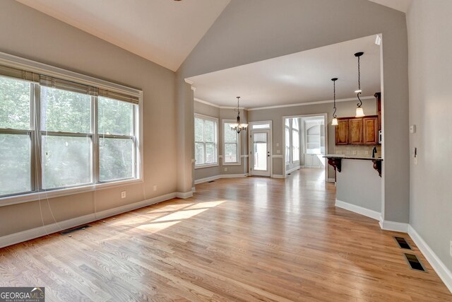 unfurnished living room featuring baseboards, light wood-style flooring, lofted ceiling, and a notable chandelier