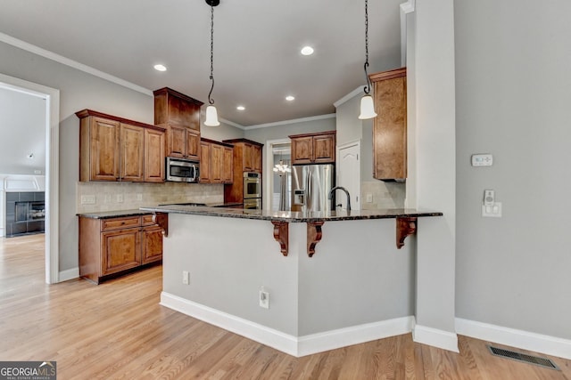 kitchen featuring visible vents, brown cabinetry, dark stone countertops, and stainless steel appliances