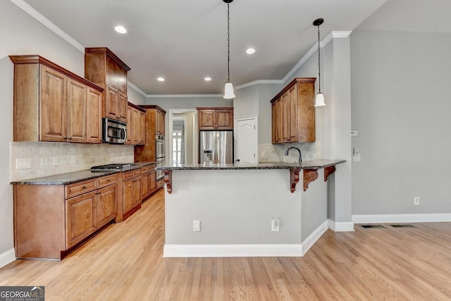 kitchen with dark stone countertops, stainless steel appliances, a peninsula, tasteful backsplash, and ornamental molding
