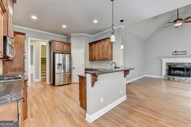 kitchen featuring a breakfast bar, stainless steel appliances, open floor plan, a ceiling fan, and a peninsula