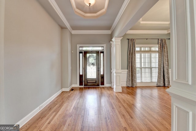 foyer featuring a healthy amount of sunlight, crown molding, decorative columns, and light wood-style flooring
