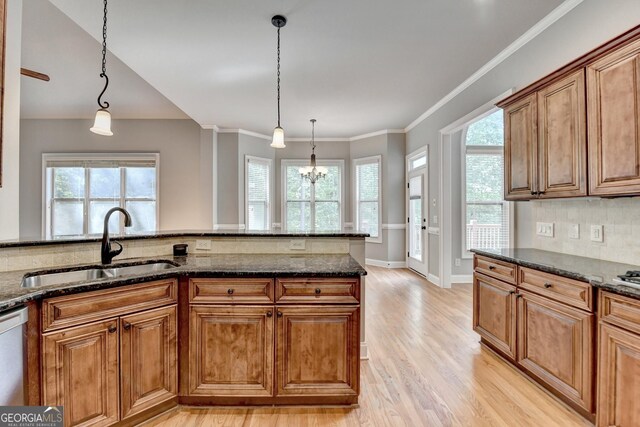 kitchen featuring a sink, light wood-style flooring, brown cabinets, and pendant lighting