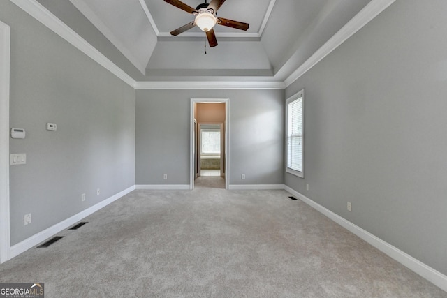 carpeted empty room with ceiling fan, visible vents, baseboards, and a raised ceiling