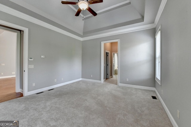 carpeted spare room with baseboards, a ceiling fan, a raised ceiling, and visible vents