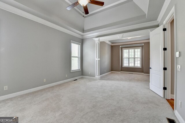 spare room with a ceiling fan, a tray ceiling, light carpet, and baseboards