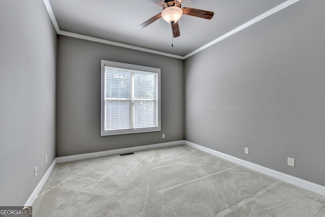 carpeted empty room with crown molding, baseboards, a ceiling fan, and visible vents