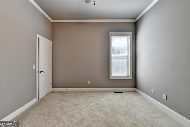 empty room with crown molding, baseboards, visible vents, and light colored carpet