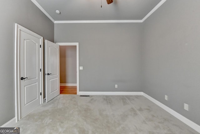 unfurnished bedroom featuring crown molding, carpet floors, baseboards, and a ceiling fan